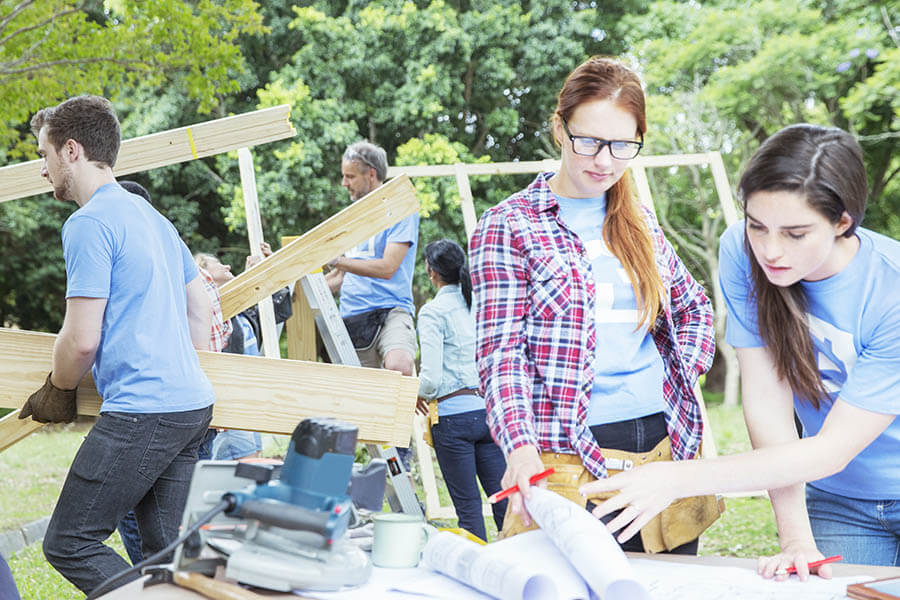 volunteers moving house construction materials around a build site