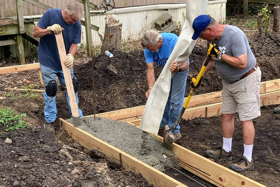 habitat for humanity volunteers pouring a concrete house foundation