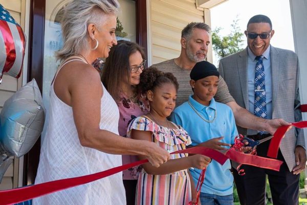 family cutting the ribbon at a habitat for humanity build reveal