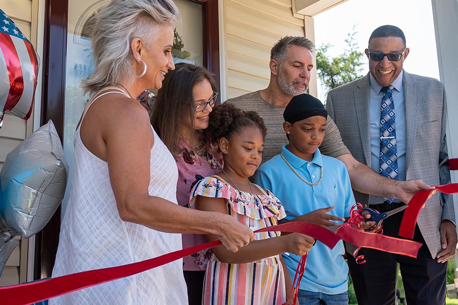 family cutting the ribbon at a habitat for humanity house reveal in alton illinois